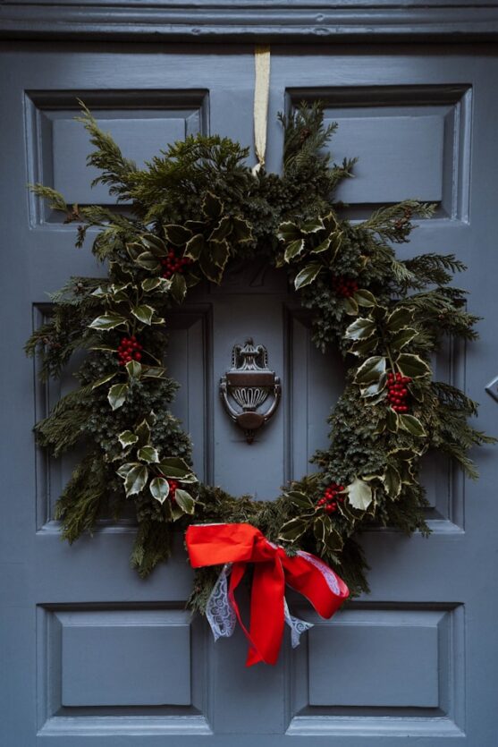 Christmas wreath with needles leaves and berry leaves decorated with red ribbon