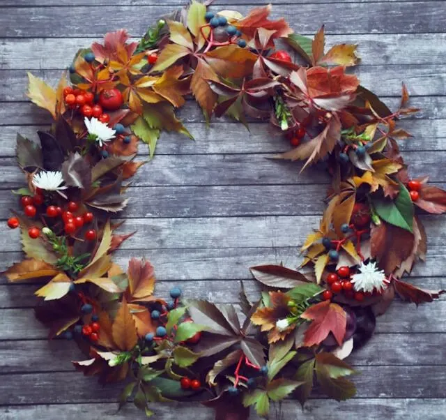 creative Christmas wreath with colorful leaves and decorated with red berries 